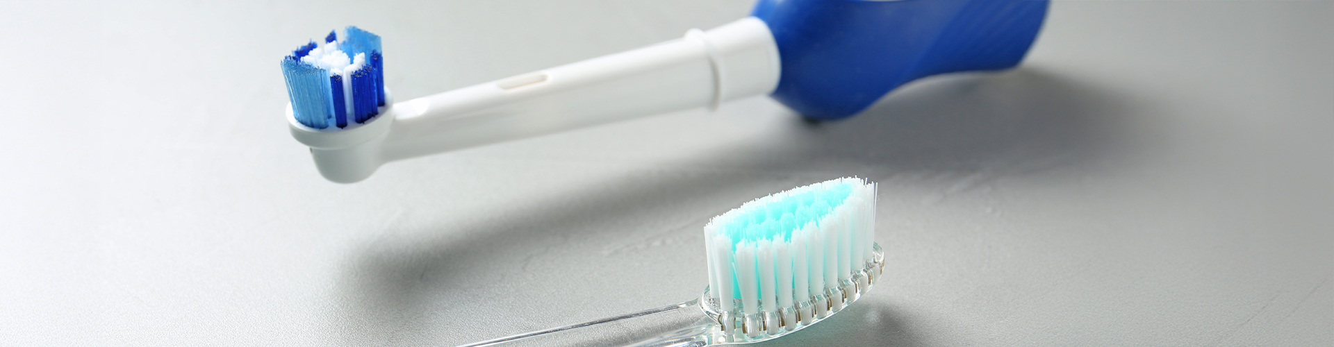 Electric and manual toothbrushes laying beside each other.
